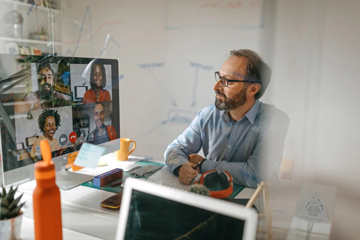 Man in glasses explaining something across a table in a bright office, likely in a consulting or service role.