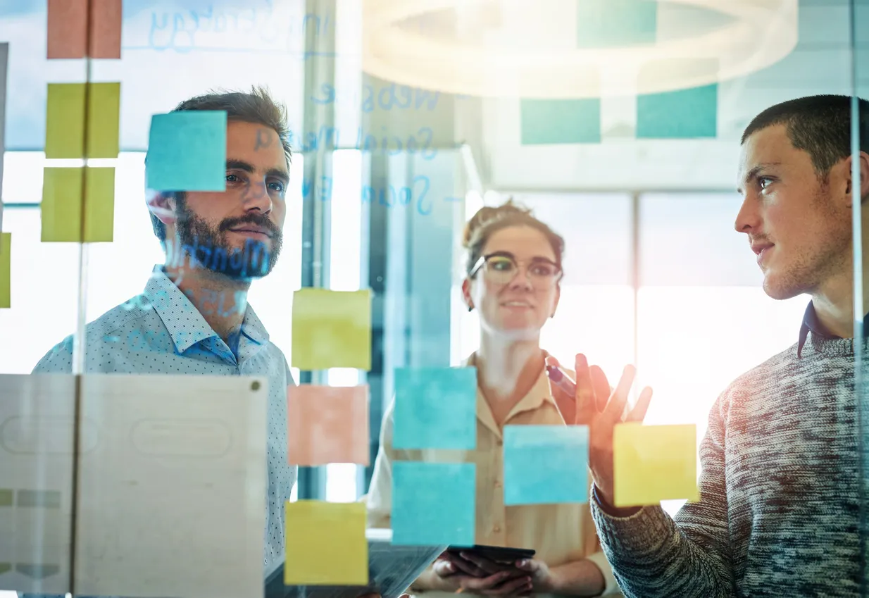 Mixed-gender group collaborating in a modern, bright office setting.